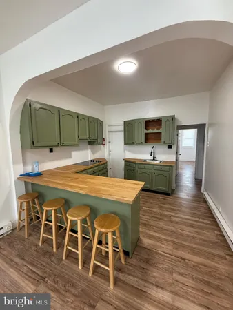a living room with stainless steel appliances kitchen island granite countertop furniture and a wooden floor