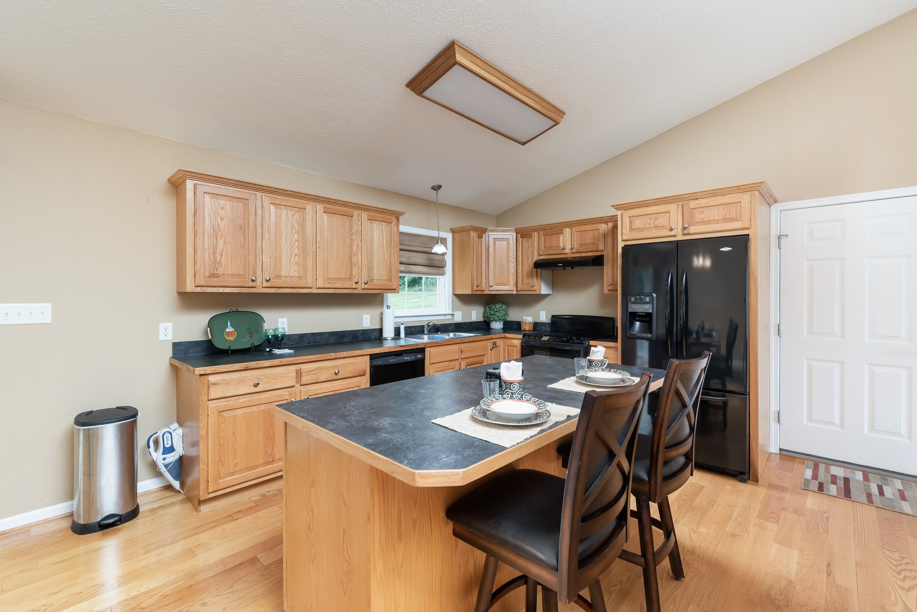 3934 Shutterlee Mill Road Staunton, VA 24401 - Photo 14 of 49 a kitchen with a refrigerator a stove top oven a sink dishwasher and white cabinets with wooden floor