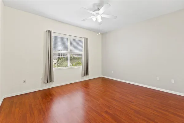 a view of an empty room with wooden floor and a window