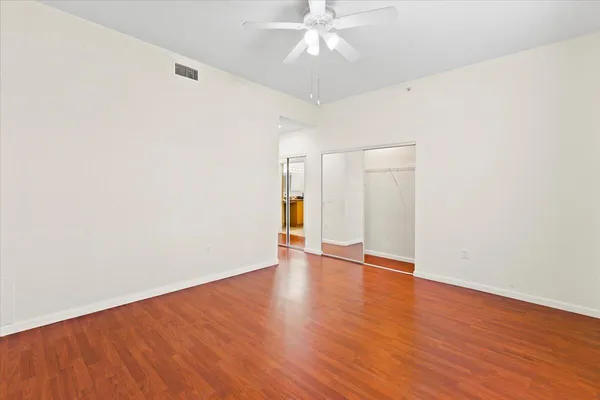 an empty room with wooden floor and windows