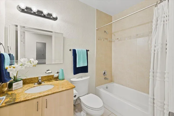 a bathroom with a granite countertop sink a toilet a mirror a vanity and shower