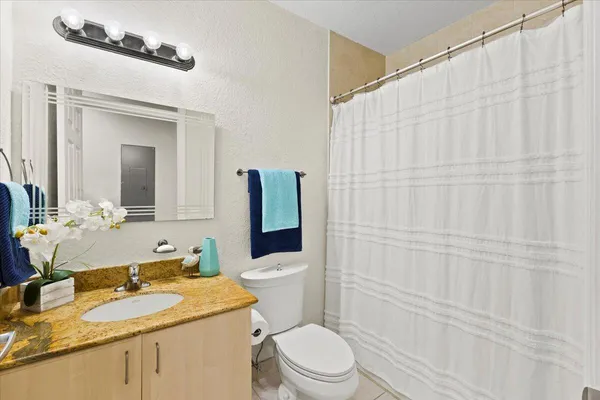 a bathroom with a granite countertop sink vanity mirror and toilet