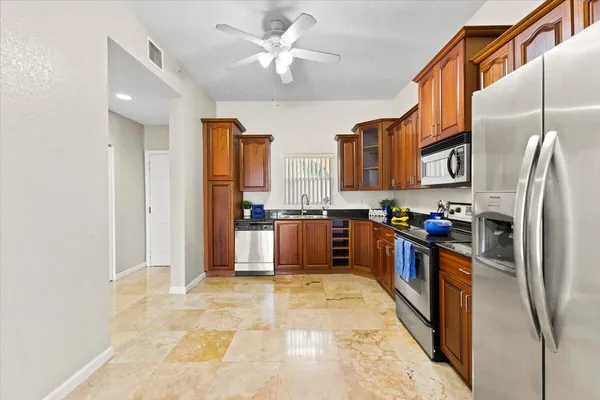 a kitchen with stainless steel appliances granite countertop a refrigerator a stove and a sink