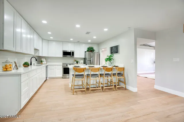 a large white kitchen with lots of furniture a sink a dining table and chairs