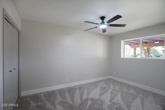 an empty room with windows and fan