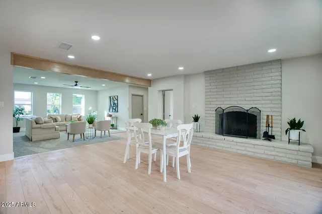 a living room with furniture a fireplace and a dining table with wooden floor