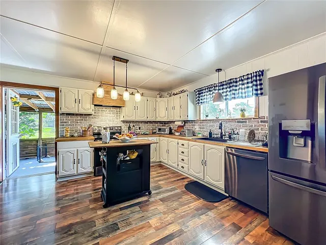 a large kitchen with stainless steel appliances granite countertop a stove a sink dishwasher a refrigerator and wooden floor