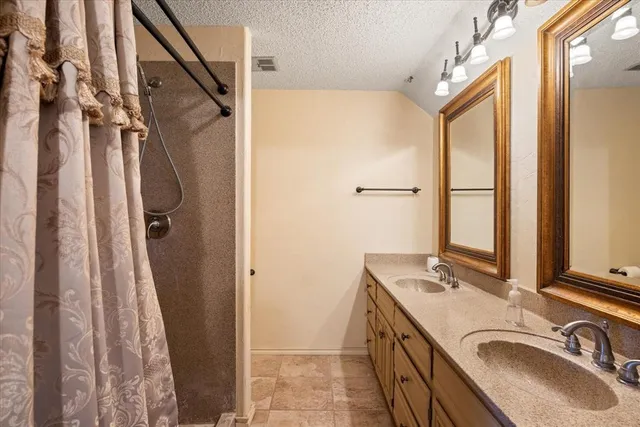 a bathroom with a granite countertop sink a mirror and a shower