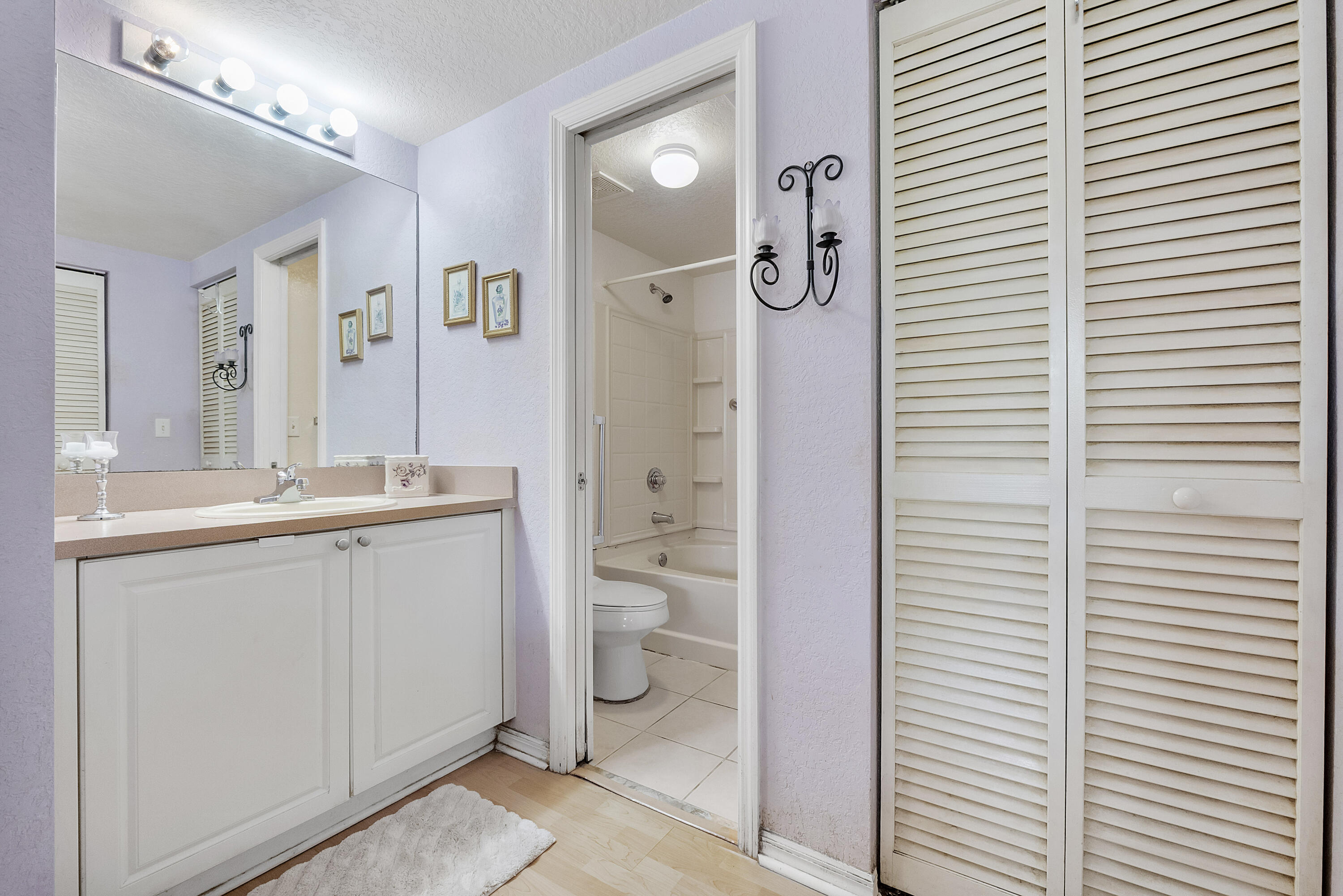 6592 West Sample Road, Unit 6592 Coral Springs, FL 33067 - Photo 22 of 42 a bathroom with a granite countertop toilet a sink and a mirror
