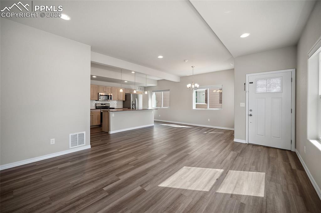 7768 Bone Crk Road Colorado Springs, CO 80924 - Photo 8 of 25 a view of empty room with wooden floor and kitchen