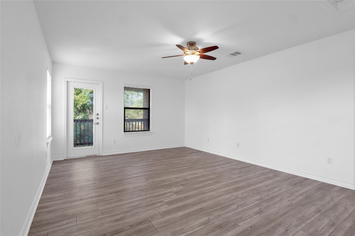 10217 English Oak Drive Austin, TX 78748 - Photo 18 of 31 an empty room with wooden floor chandelier fan and windows