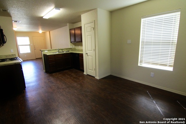 a living room with hard wood floors and a kitchen counter space