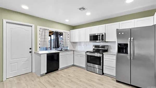 a kitchen with stainless steel appliances granite countertop a stove top oven a sink and a refrigerator