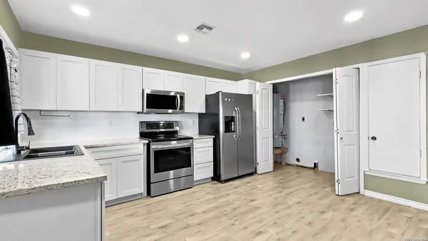 a kitchen with stainless steel appliances granite countertop a refrigerator and a stove top oven