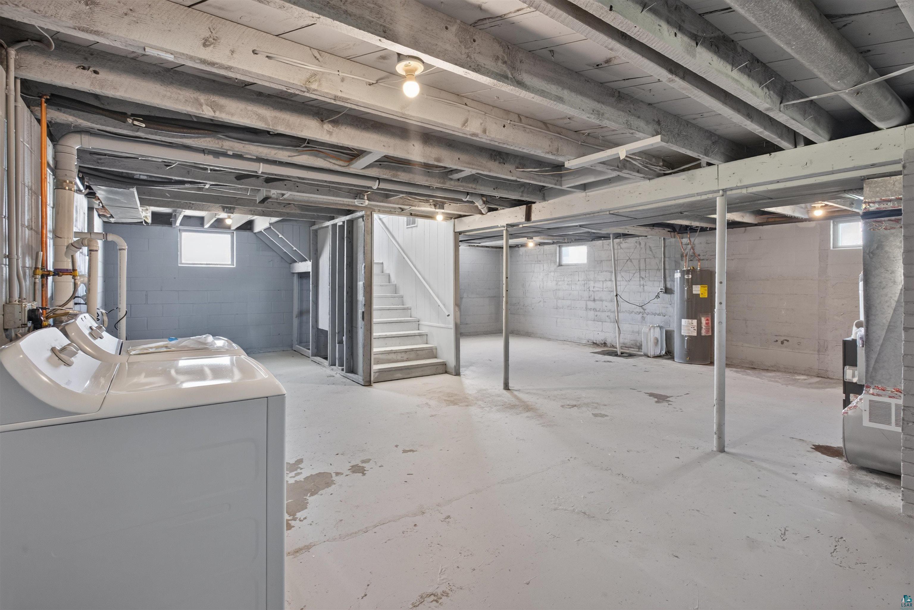 5868 Rice Lake Road Duluth, MN 55803 - Photo 28 of 39 Expansive unfinished basement featuring concrete block walls, exposed ceiling joists, multiple windows, and a utility area with water heater and furnace