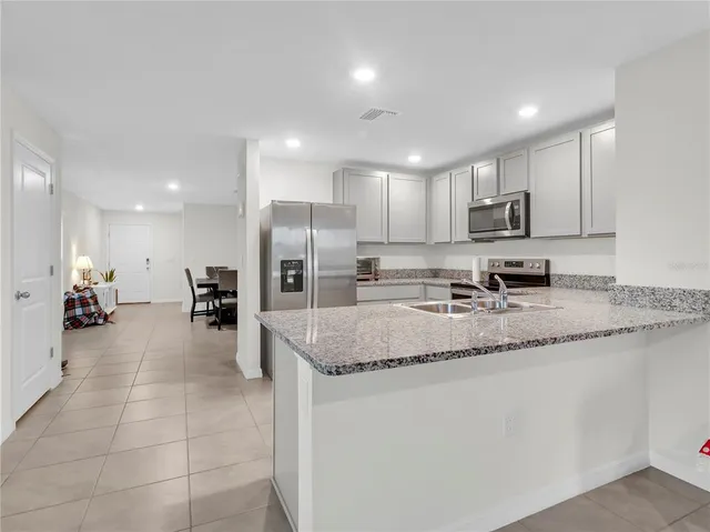 a kitchen with stainless steel appliances granite countertop a sink refrigerator and cabinets