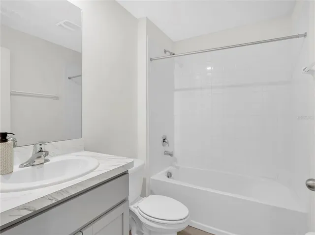 a bathroom with a granite countertop sink a toilet and shower