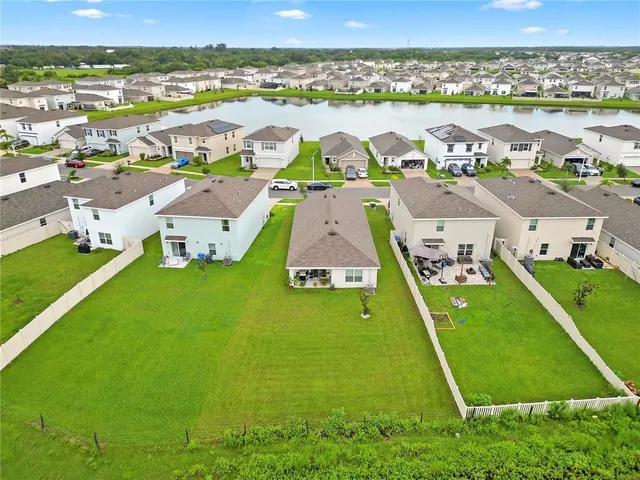 an aerial view of residential houses with outdoor space and a lake view