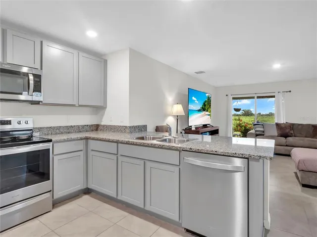 a kitchen with granite countertop a sink stainless steel appliances and cabinets