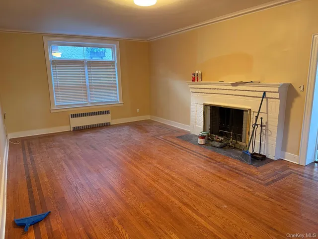 an empty room with wooden floor fireplace and windows