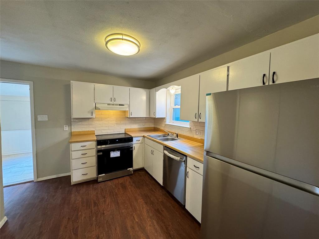 2004 Throckmorton Street Gainesville, TX 76240 - Photo 20 of 24 a kitchen with stainless steel appliances granite countertop a refrigerator a stove and a sink