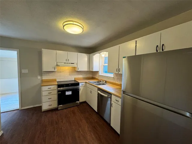 a kitchen with stainless steel appliances granite countertop a refrigerator a stove and a sink