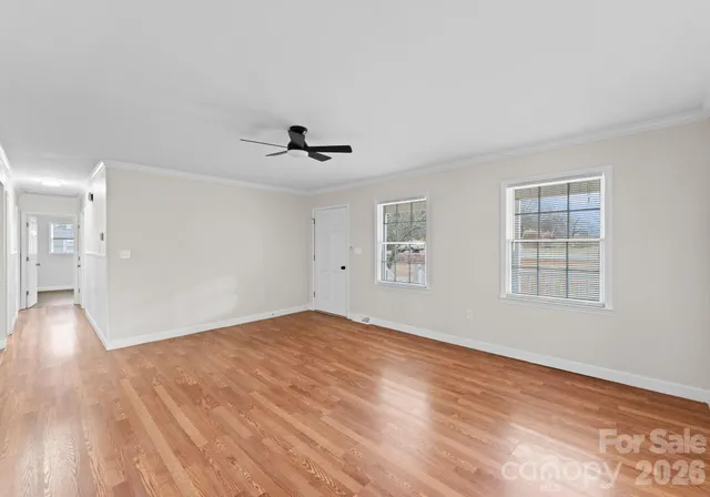 a view of empty room with wooden floor and fan