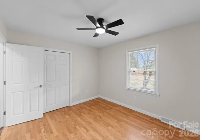 a view of a room with wooden floor and a ceiling fan