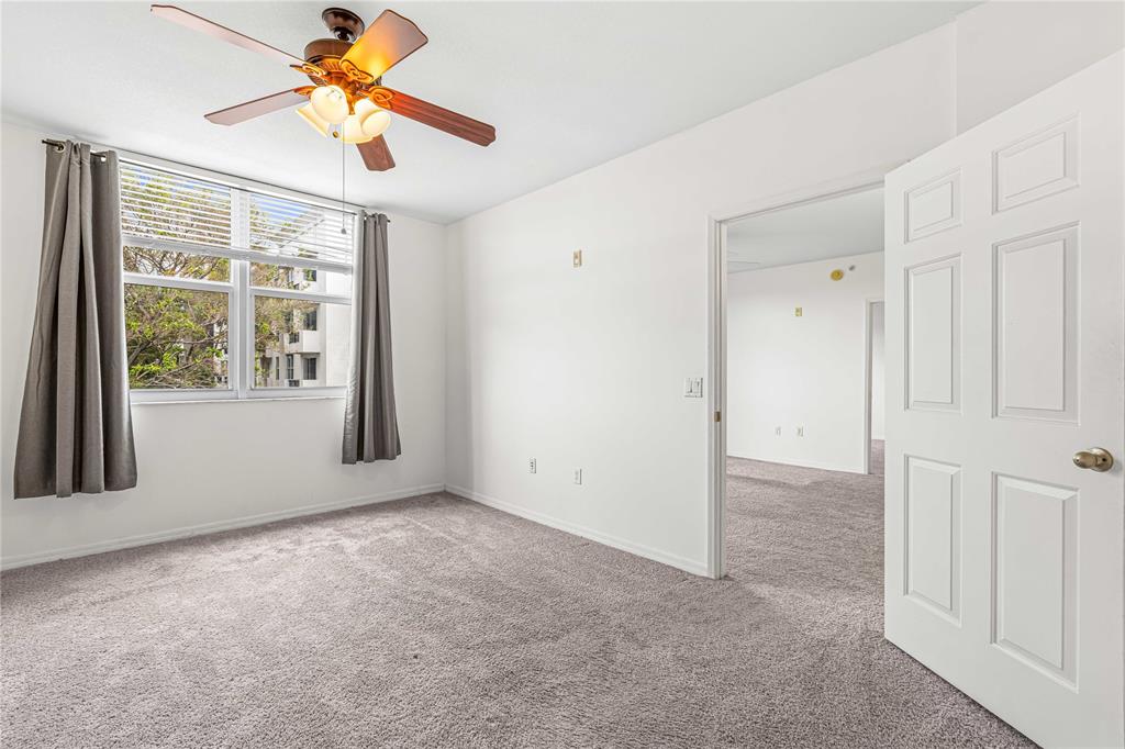 2421 Northeast 65th Street, Unit 318 Fort Lauderdale, FL 33308 - Photo 15 of 31 an empty room with windows and a chandelier fan