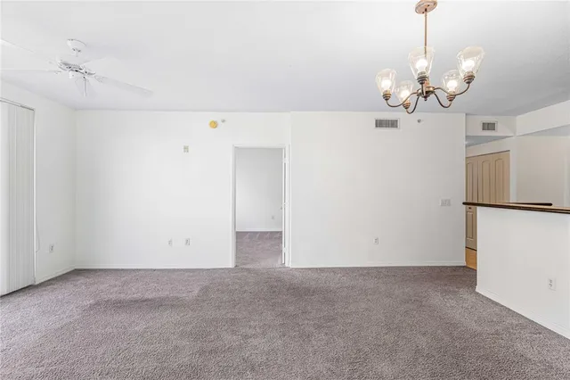 a view of an empty room with a chandelier fan