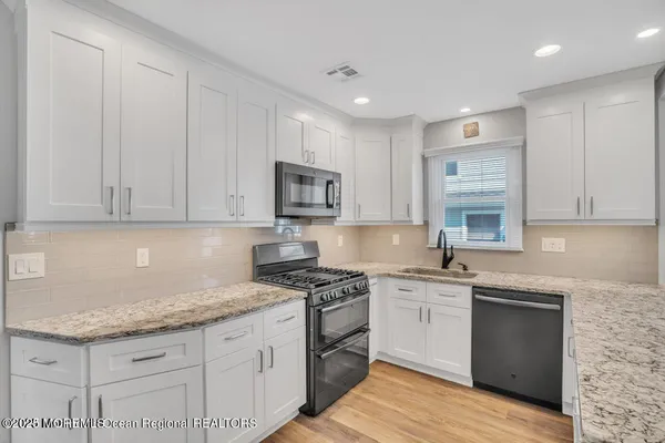 a kitchen with granite countertop a sink a stove and cabinets