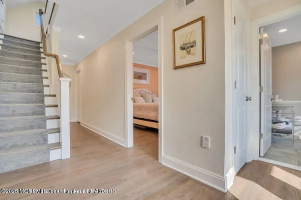a view of a hallway with bathroom and wooden floor