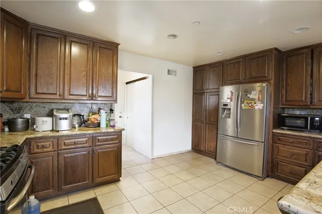 a kitchen with granite countertop a refrigerator and a stove top oven