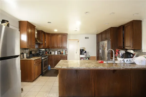 a kitchen with kitchen island granite countertop a sink cabinets and stainless steel appliances