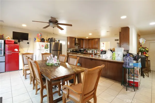 a dining area with stainless steel appliances kitchen island granite countertop a dining table chairs and a refrigerator