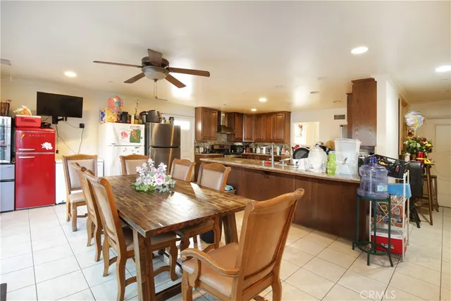 a dining area with stainless steel appliances kitchen island granite countertop a dining table chairs and a refrigerator