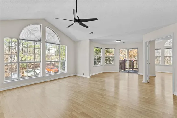 a view of an empty room with a window and wooden floor