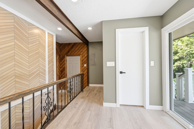 Hallway featuring wood-finish flooring, recessed lighting, and a decorative wood-paneled accent wall