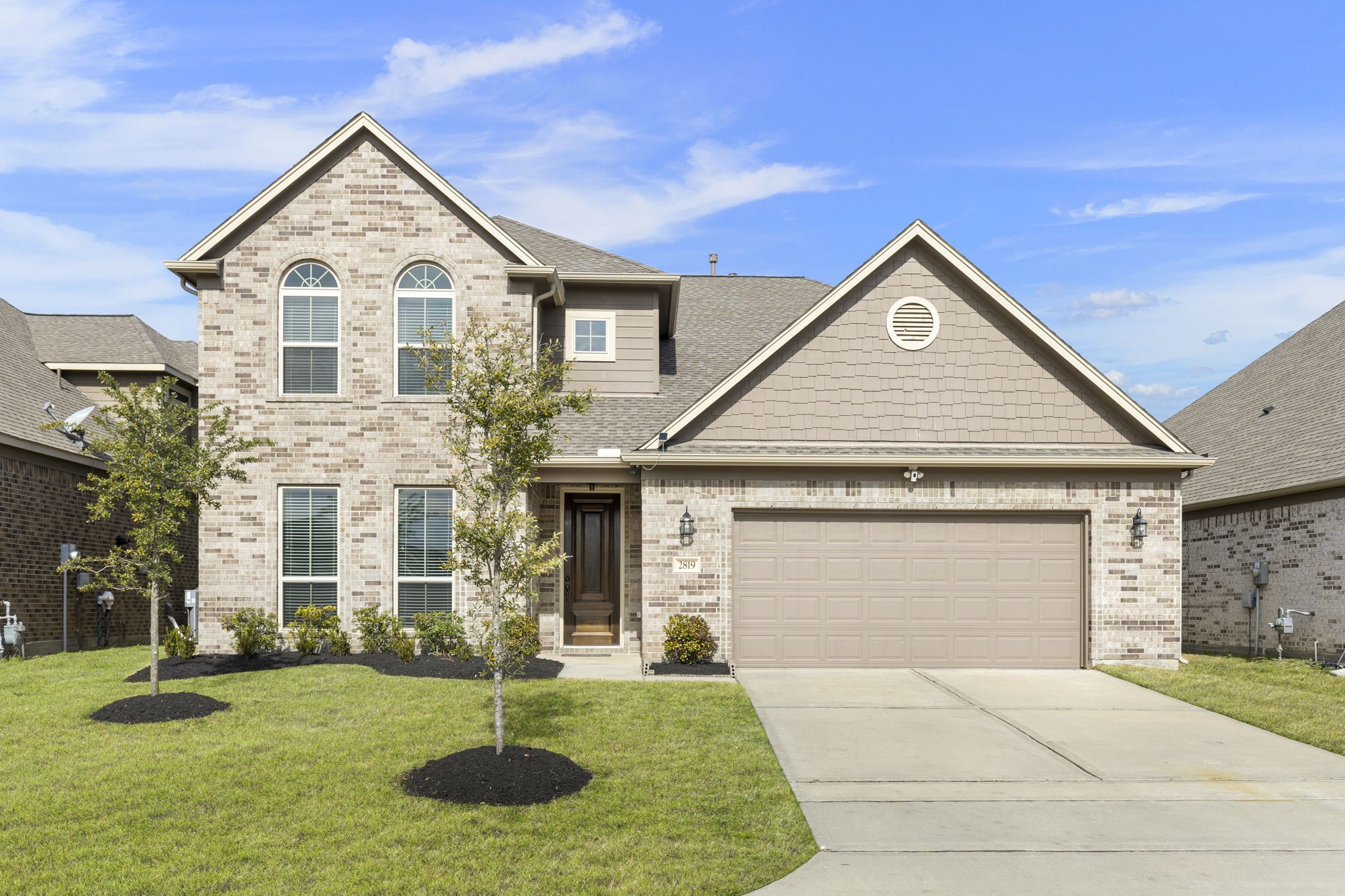 Discover your dream home with this charming front house, featuring elegant brickwork and a spacious two-car garage, set amidst a beautifully landscaped lawn under a clear blue sky.