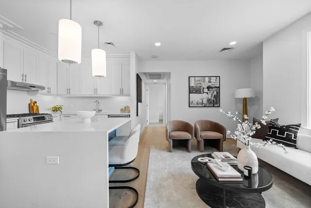 a living room with furniture couches and kitchen view with wooden floor