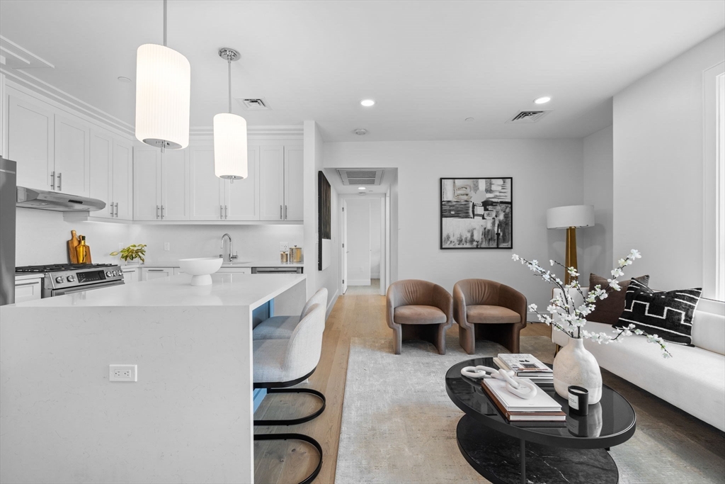 301 Border Street, Unit 409 Boston, MA 02128 - Photo 3 of 23 a living room with furniture couches and kitchen view with wooden floor