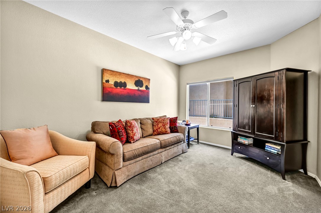 10730 Amber Ridge Drive, Unit 101 Las Vegas, NV 89144 - Photo 6 of 32 A relaxed living area offers comfort with carpeted floors and a window view.