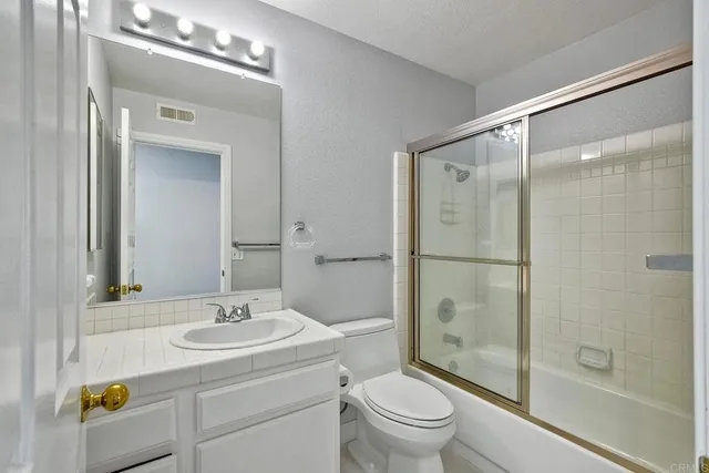 a bathroom with a shower sink vanity mirror and toilet
