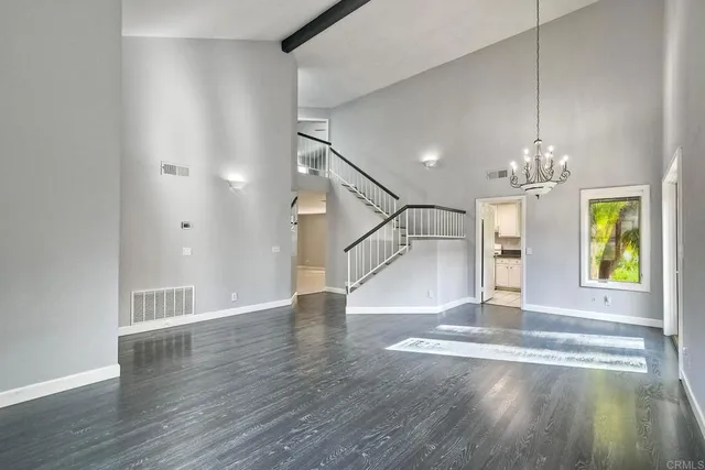 a view of an empty room with window and wooden floor