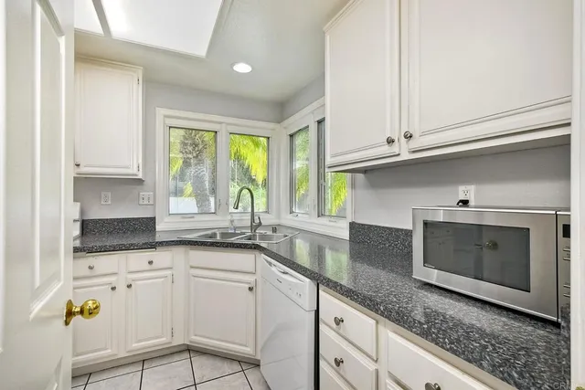 a kitchen with granite countertop white cabinets and white appliances