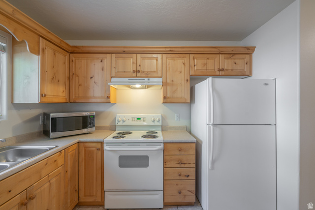 1735 West 540 North, Unit 1805 St. George, UT 84770 - Photo 26 of 64 Efficient kitchen featuring light wood cabinetry, a double basin stainless steel sink, and light-colored countertops