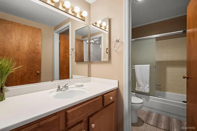 a bathroom with a sink a toilet a mirror and shower