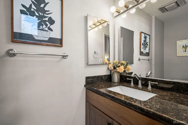 a bathroom with a granite countertop sink and a mirror