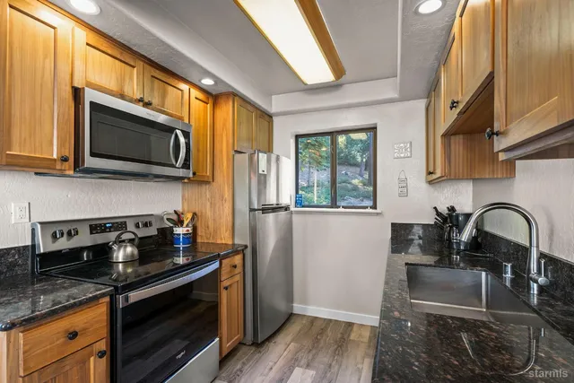 a kitchen with granite countertop a stove a sink and a microwave