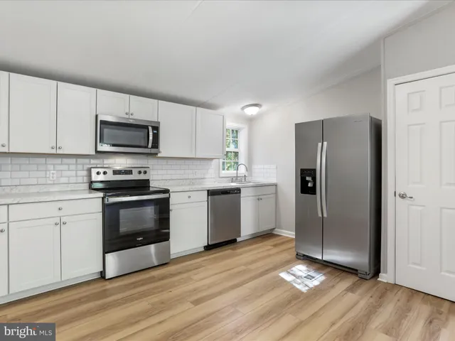 an empty room with wooden floor cabinet and windows